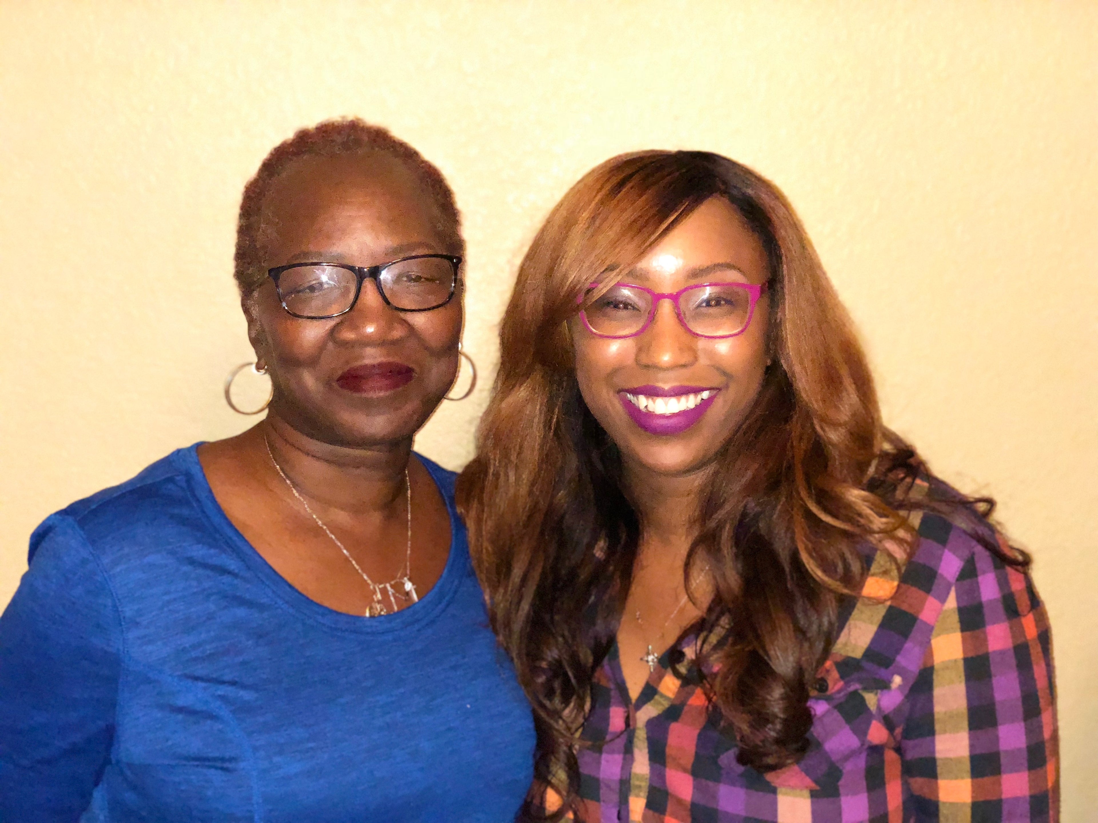 Two women posing together against a plain background