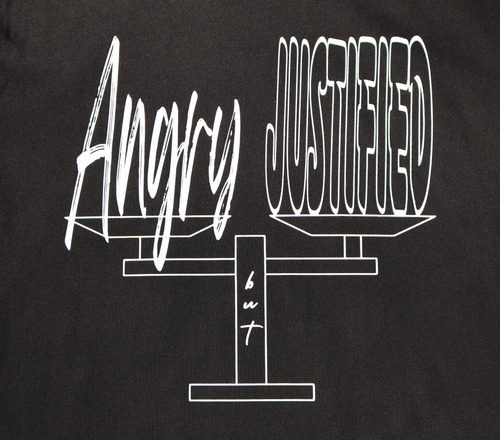 Zoomed in view of black t-shirt with white 'Angry but Justified' graphic design. 