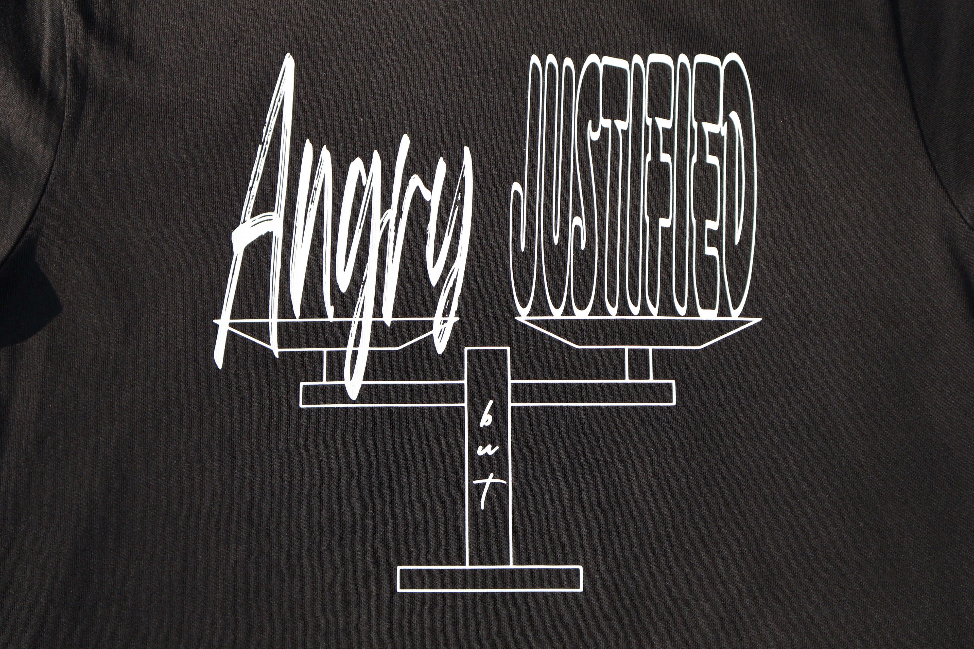 Close up of Black t-shirt with white 'Angry but Justified' text and graphic design. 