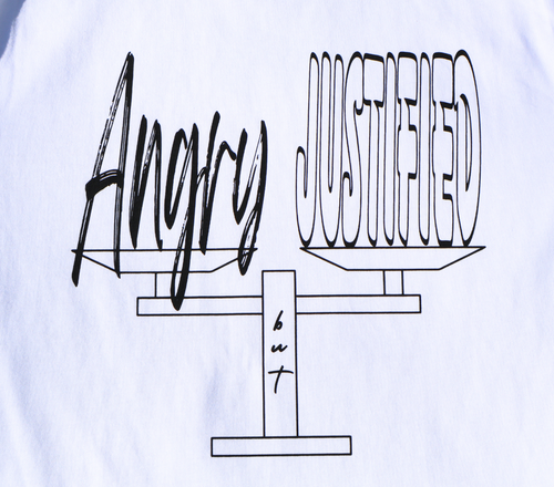 Zoomed in view of white t-shirt with black 'Angry but Justified' graphic design.