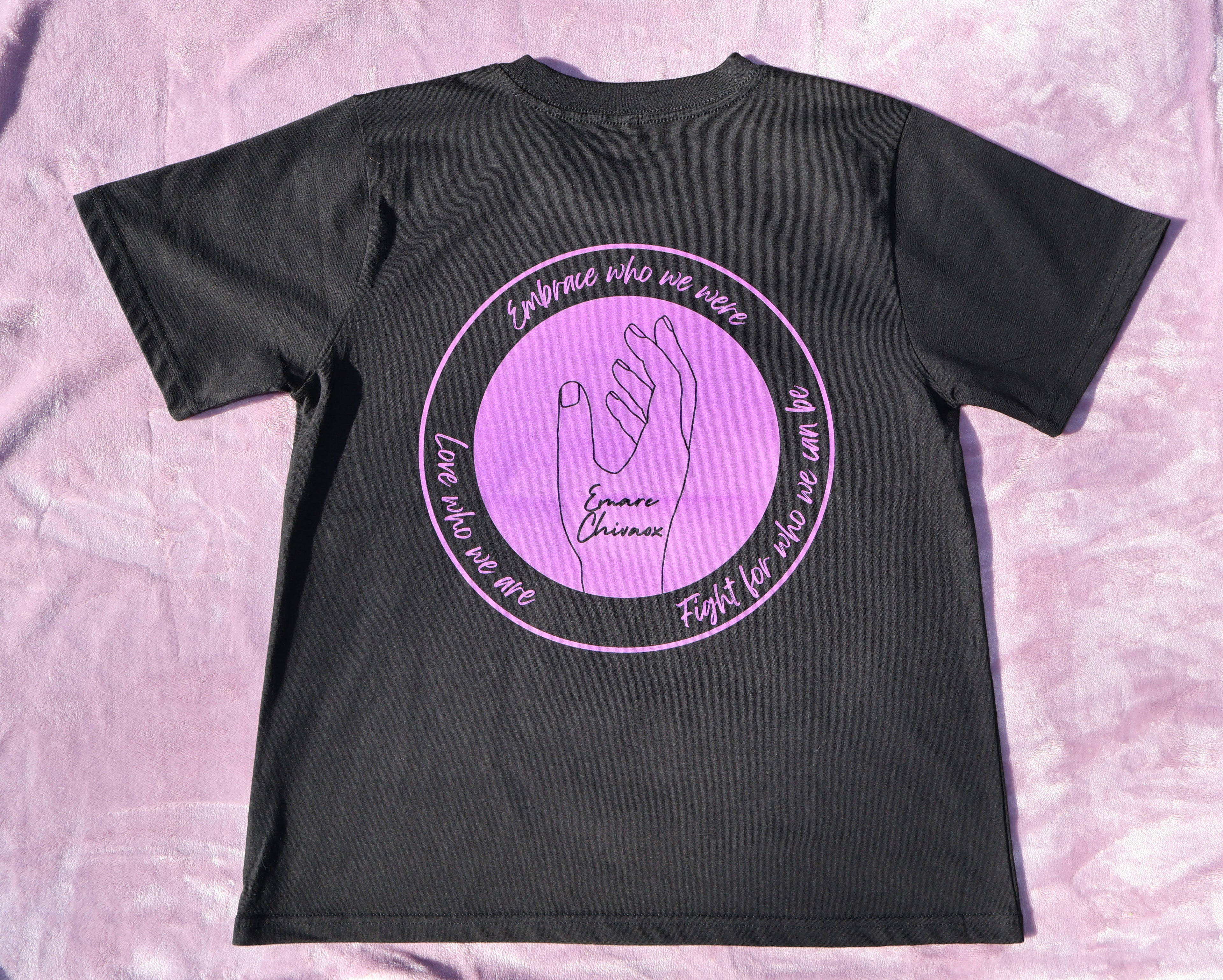 Back of a black t-shirt with purple text and graphic design on a lavender background.
