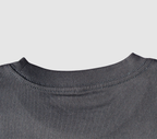 Zoomed in view of the back collar of a black t-shirt on a gray background.