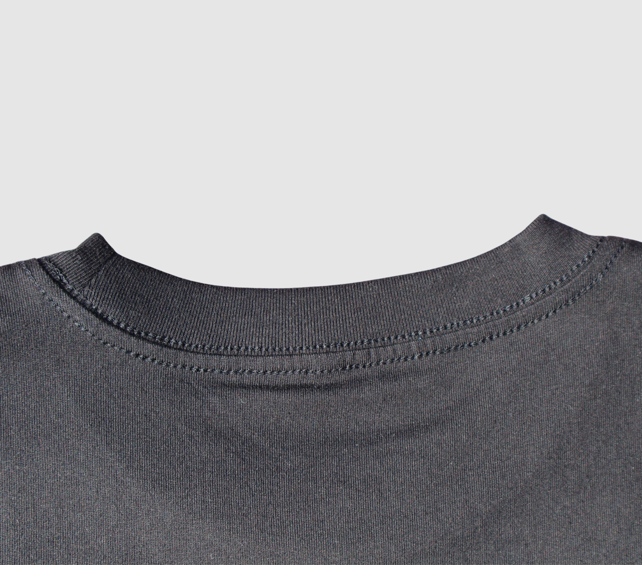 Zoomed in view of the back collar of a black t-shirt on a gray background.