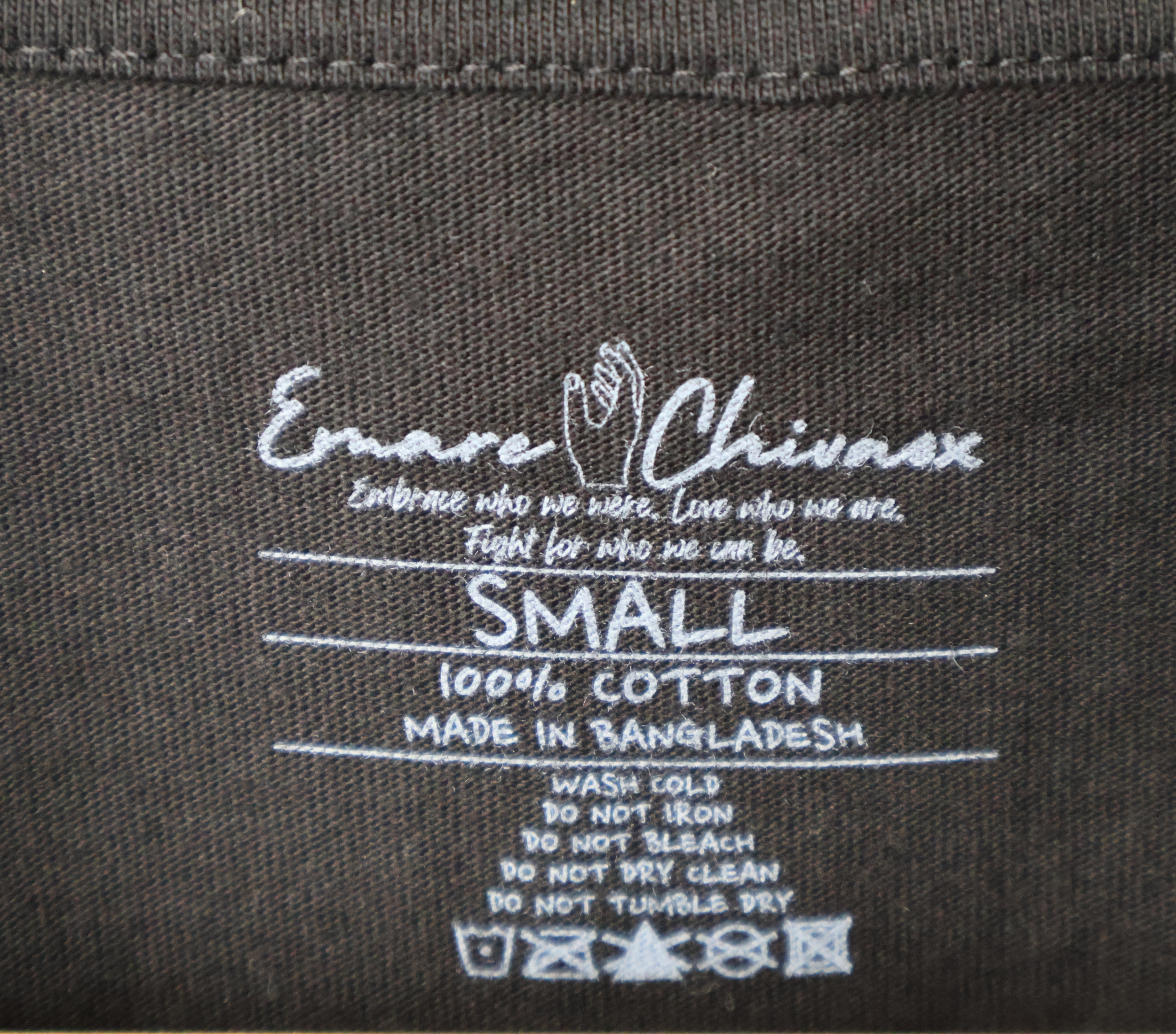 Custom next tag on a black t-shirt with white text featuring Emare Chivaox logo and slogan, shirt size, material, country of origin, and care instructions.
