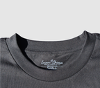 Zoomed in view of the front collar of a black t-shirt on a gray background.