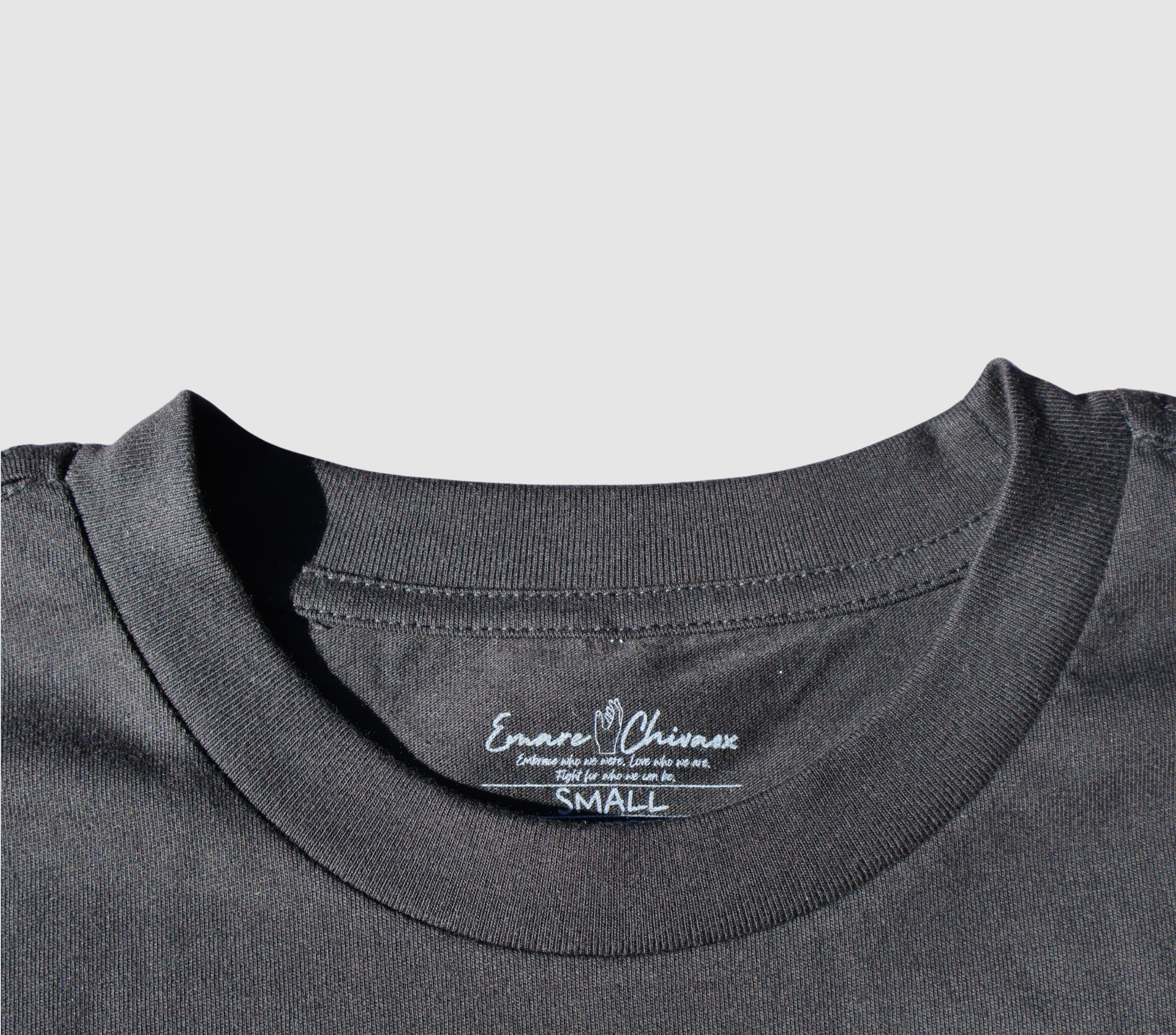 Zoomed in view of the front collar of a black t-shirt on a gray background.