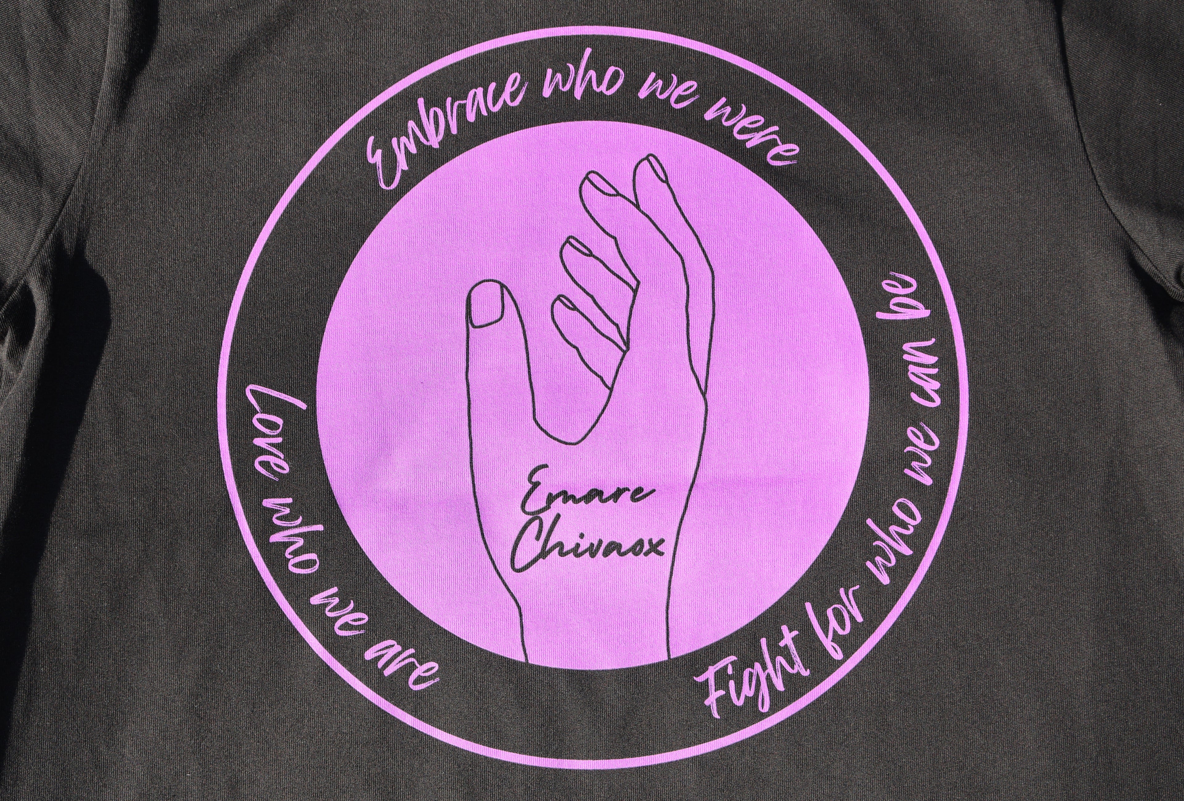 Close up of the back of a black t-shirt with purple text and graphic design.