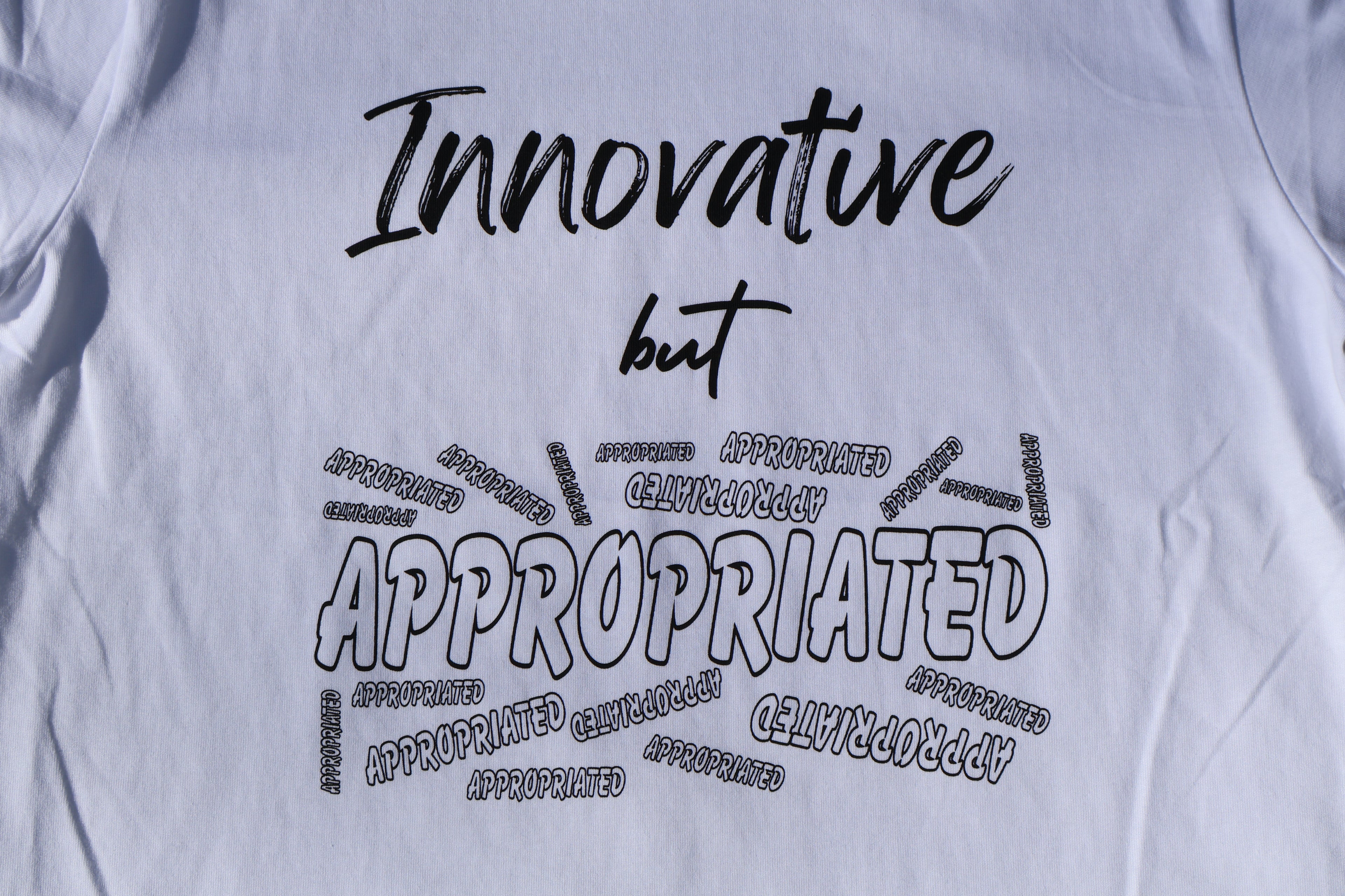 Close up of white t-shirt with black 'Innovative but Appropriated' text and graphic design. 
