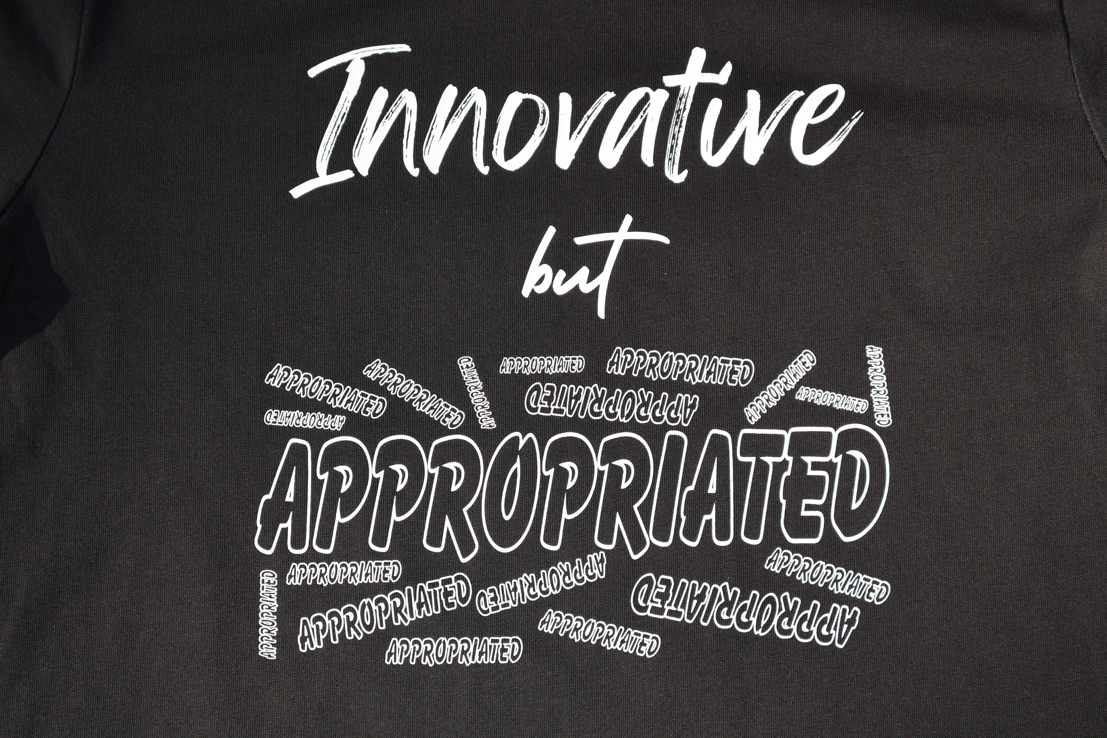 Close up of Black t-shirt with white 'Innovative but Appropriated' text and graphic design. 