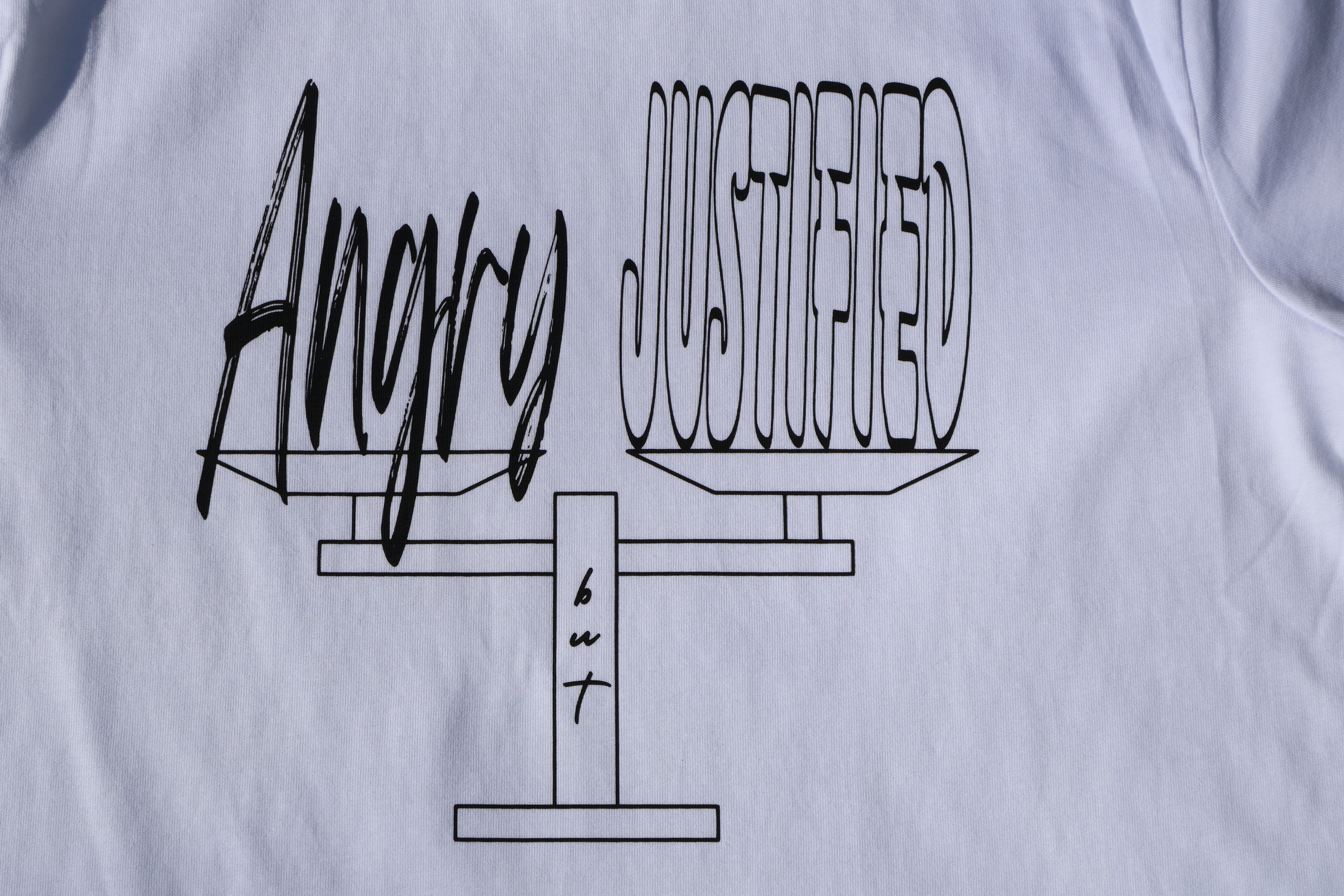 Close up of white t-shirt with black 'Angry but Justified' text and graphic design. 