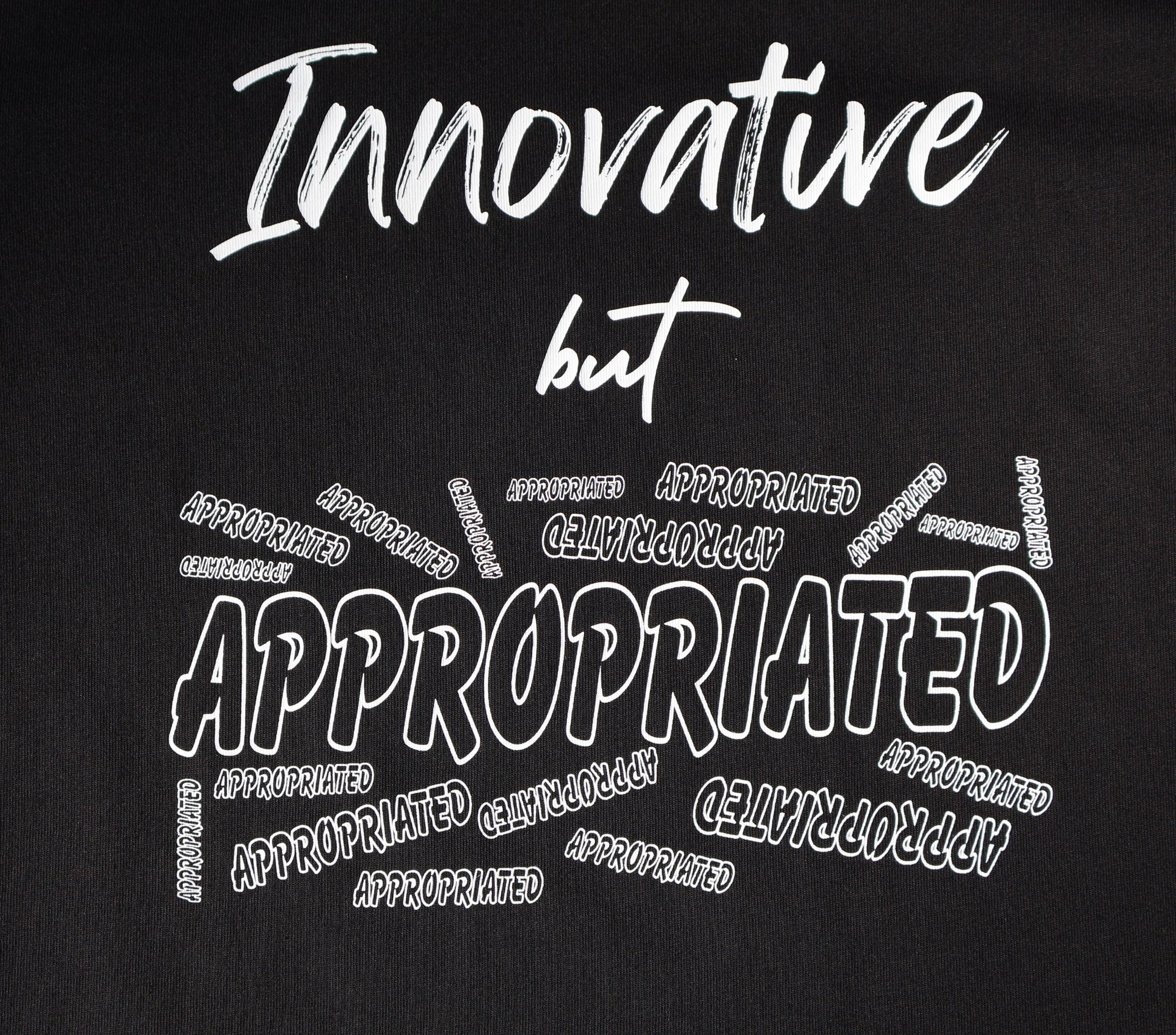 Zoomed in view of black t-shirt with white 'Innovative but Appropriated' graphic design.