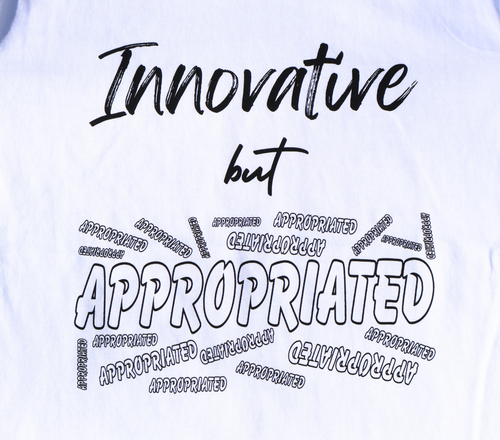 Zoomed in view of white t-shirt with black 'Innovative but Appropriated' graphic design.