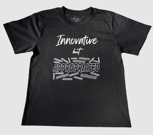 The front of a black t-shirt with white 'Innovative but Appropriated' graphic design on a gray background.