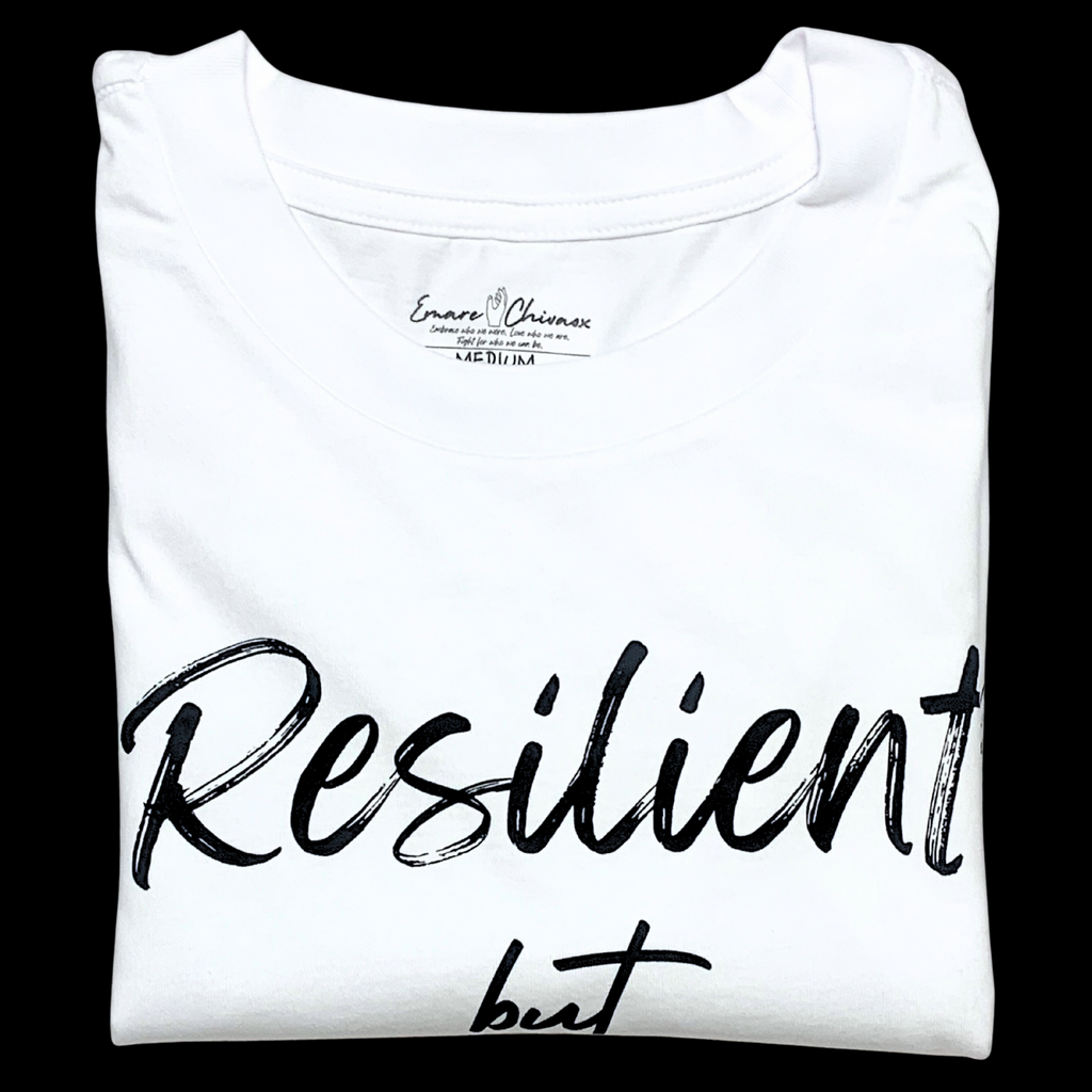 Front of white t-shirt folded with "Resilient but" black text design on a black background