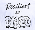Zoomed in view of white t-shirt with black 'Resilient but Tired' graphic design.