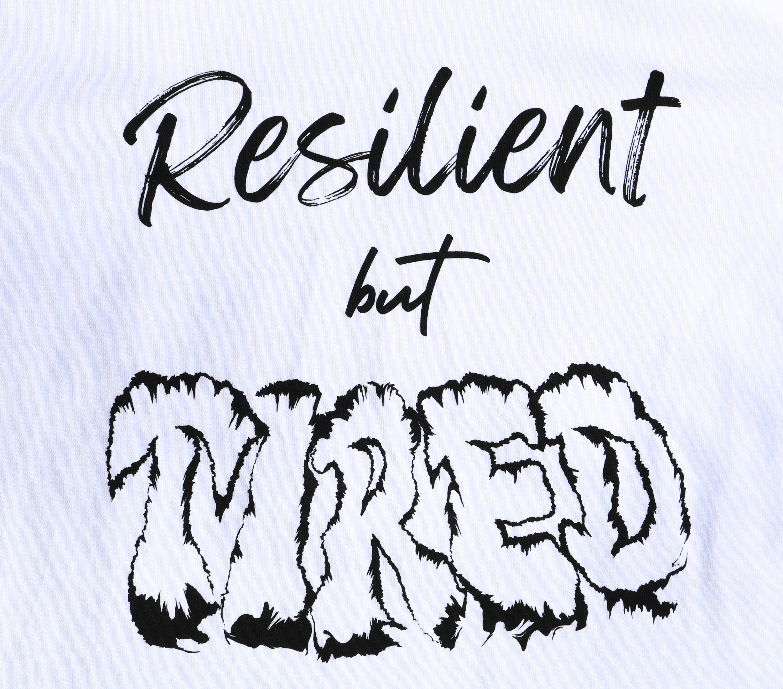 Zoomed in view of white t-shirt with black 'Resilient but Tired' graphic design.