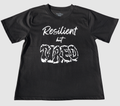 The front of a black t-shirt with white 'Resilient but Tired' graphic design on a gray background.
