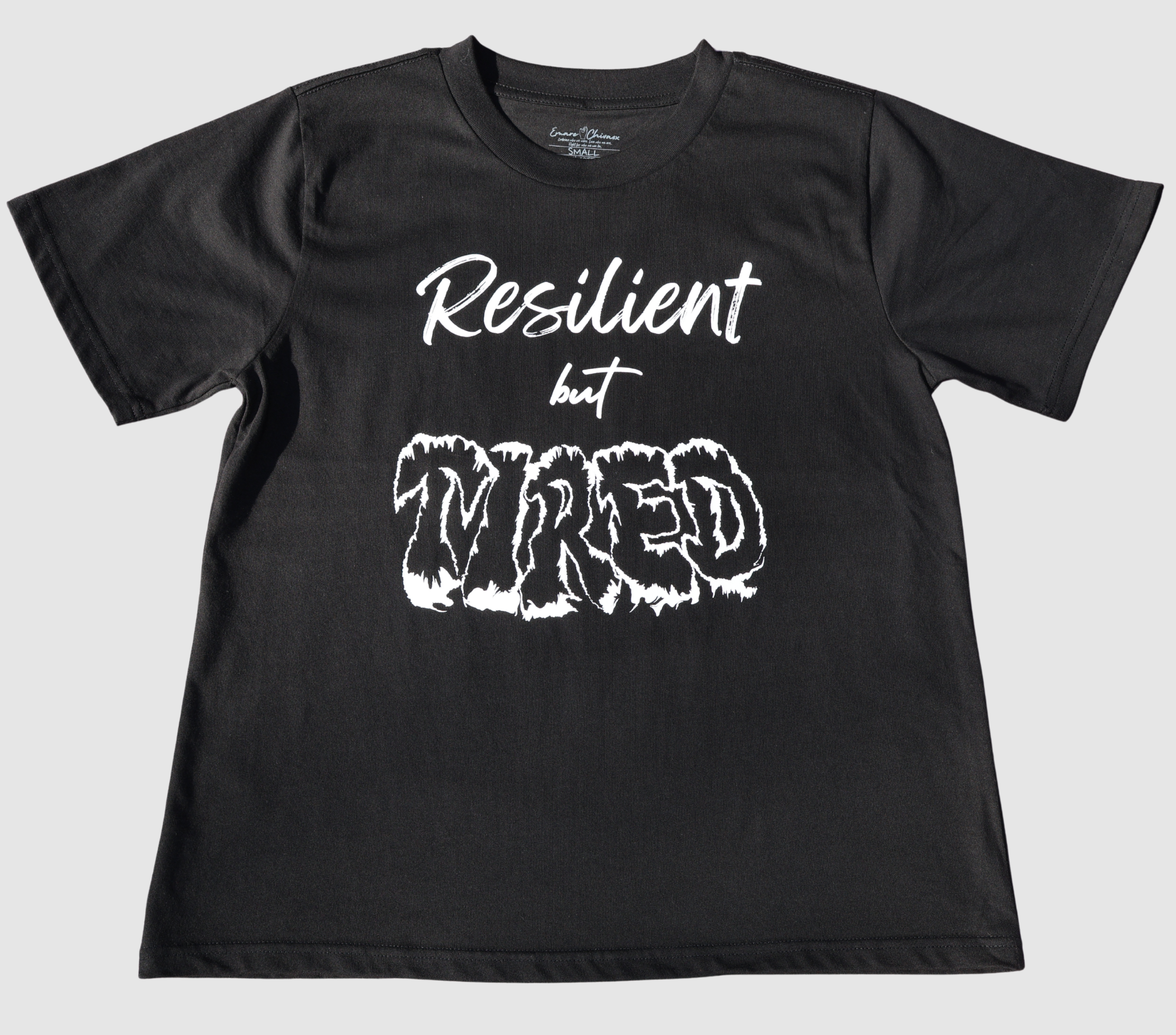 The front of a black t-shirt with white 'Resilient but Tired' graphic design on a gray background.