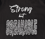 Zoomed in view of black t-shirt with white 'Strong but Breakable' graphic design.