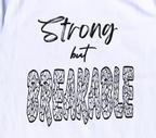 Zoomed in view of white t-shirt with black 'Strong but Breakable' graphic design.