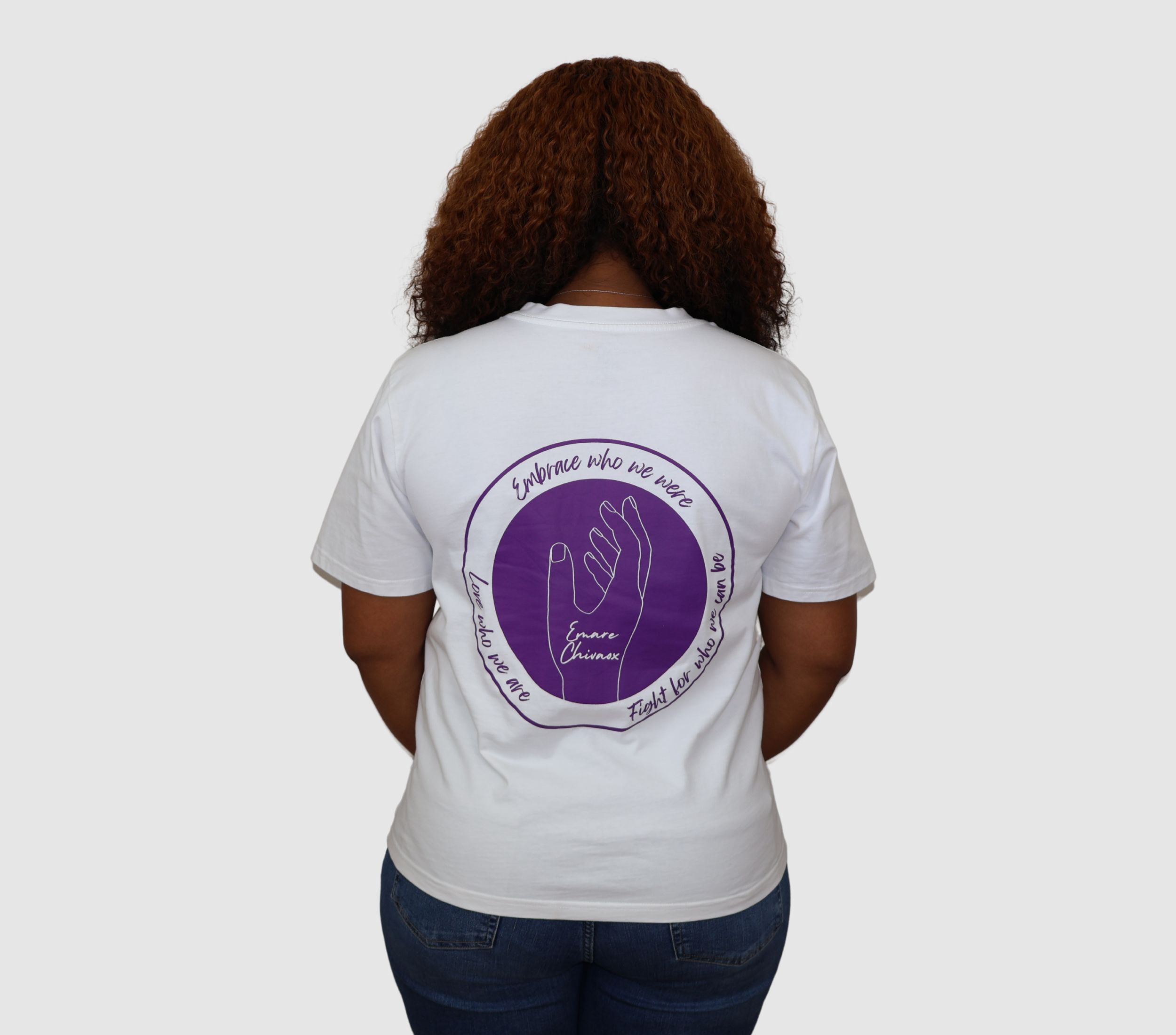 Woman wearing a white t-shirt with a purple graphic design on the back, standing against a gray background.