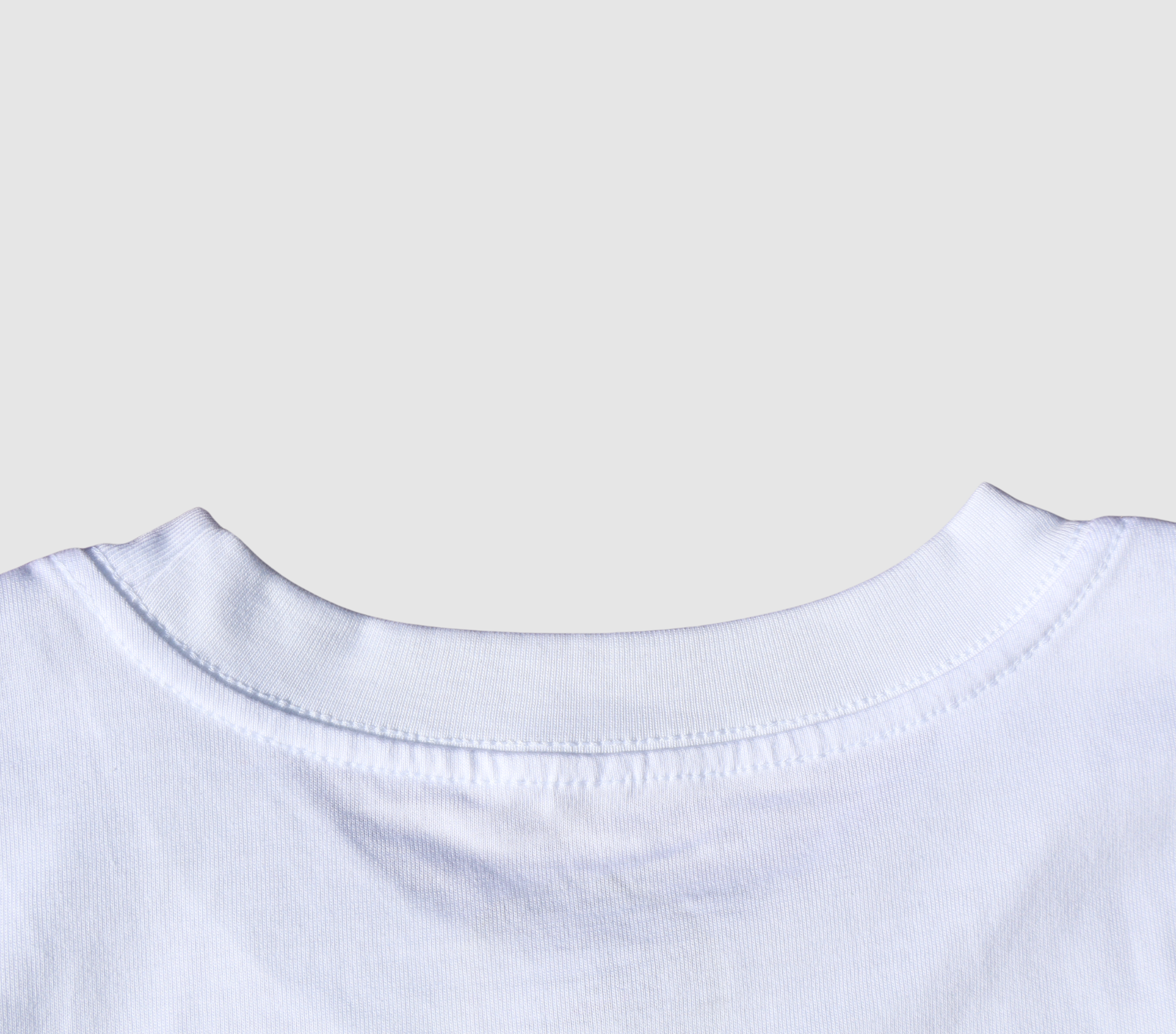 Zoomed in view of the back collar of a white t-shirt on a gray background.