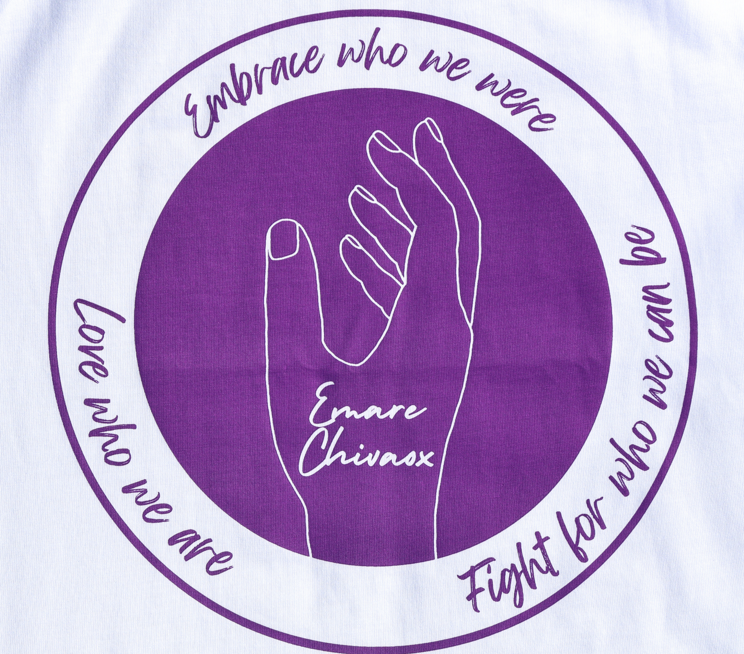 Zoomed in view of the back of a white t-shirt with a purple graphic design featuring the outline of a hand and text.